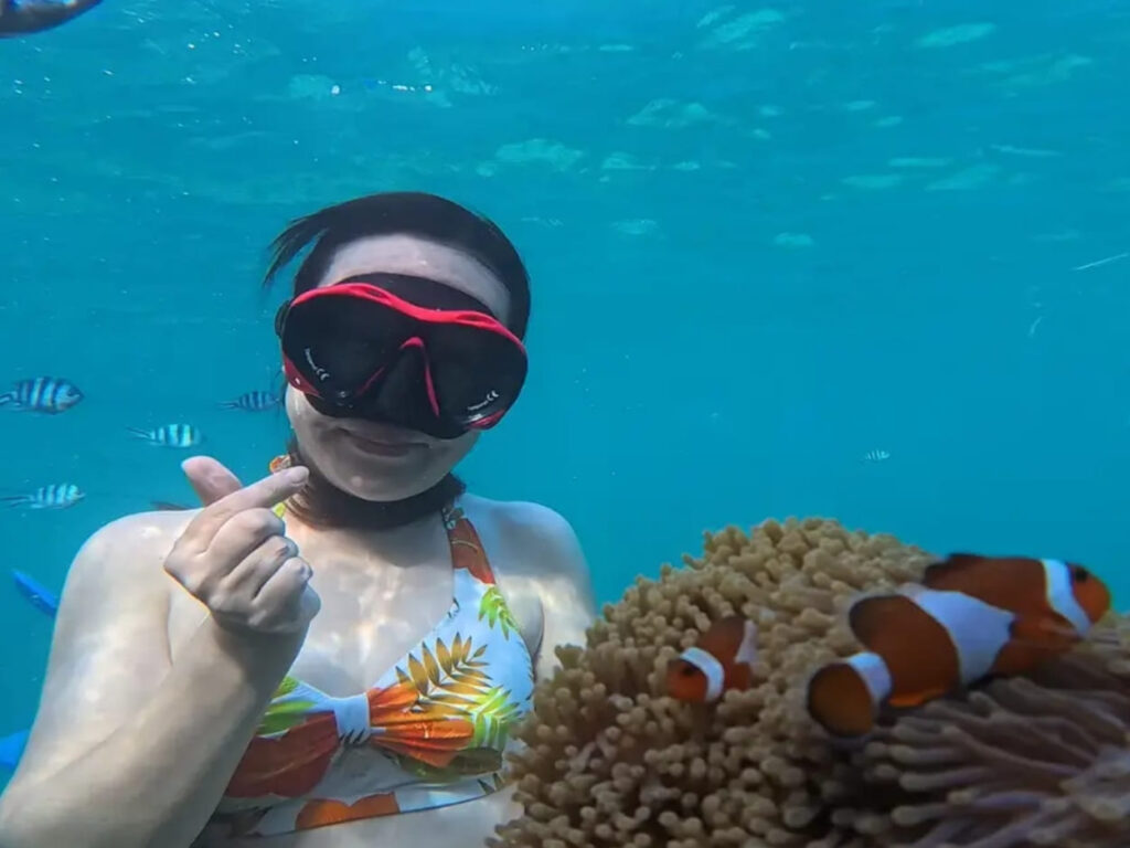 Underwater pose with clownfish and coral reef during a snorkeling experience in Bintan Tour Packages